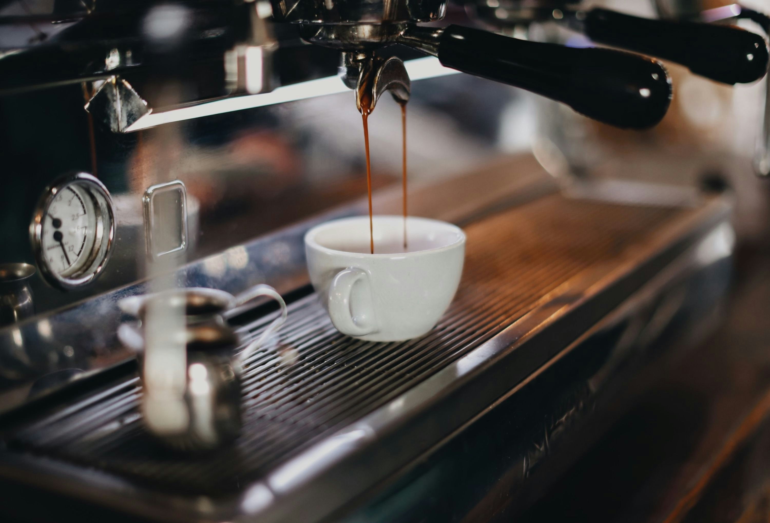 Espressomaskin som heller fersk kaffe i en hvit keramikkkopp i en koselig kaféomgivelse