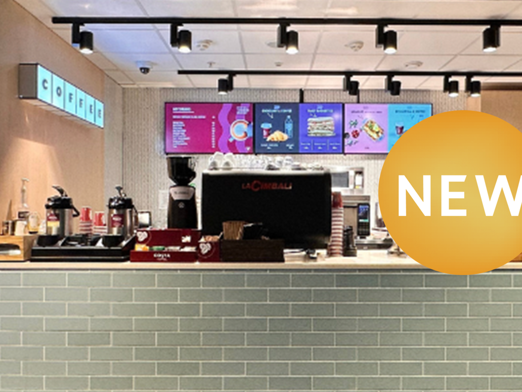 Ny kafé med moderne interiør, kaffemaskin og meny på skjermar
