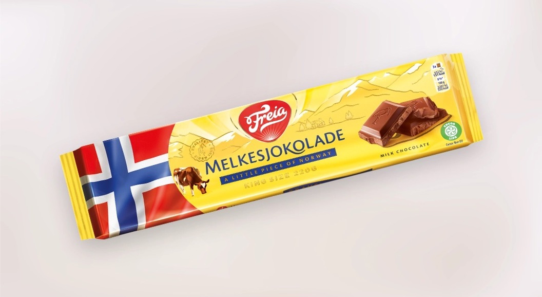 Freia Melkesjokolade-plate i gul innpakning med norsk flagg og sjokoladekvadrater, isolert på lys bakgrunn