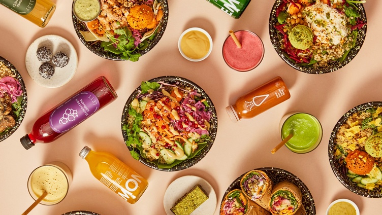 Assorterte sunne boller, wraps og drikker på en lys bakgrunn, med friske grønnsaker, korn og fargerike juicer. Ideell for et næringsrikt måltid