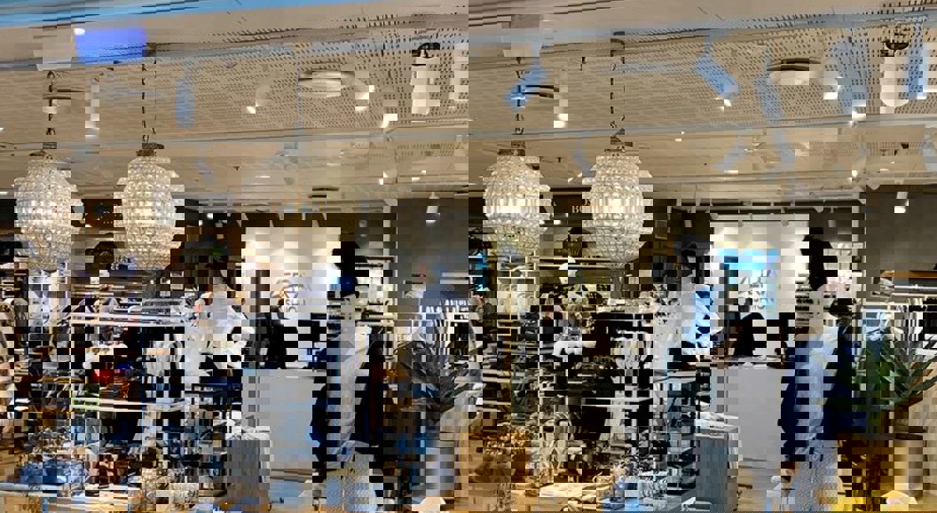 Fashion retail store entrance showcasing stylish mannequins and accessories, with prominent "AERA Fashion" signage above. The interior displays a variety of clothing and jewelry under warm lighting