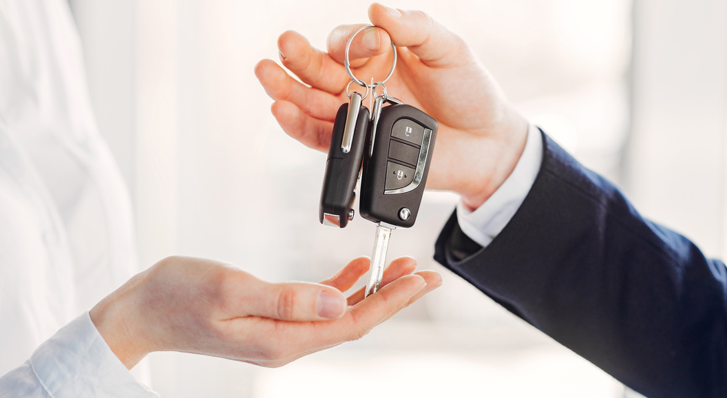Person handing over car keys to another person, symbolizing car sale or rental transaction