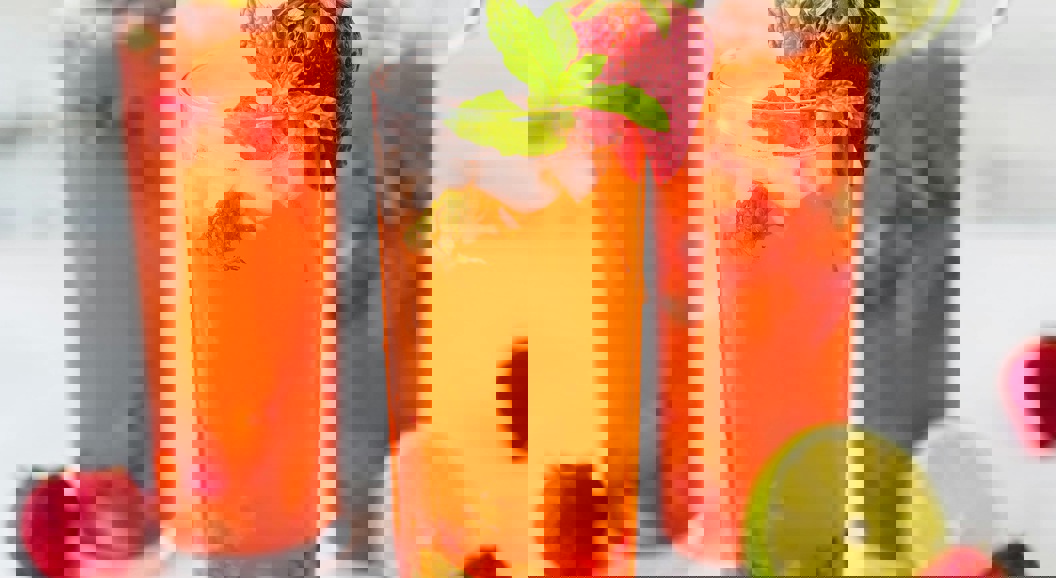 Refreshing strawberry mojito cocktails with mint leaves and lime slices, served in tall glasses on a light background