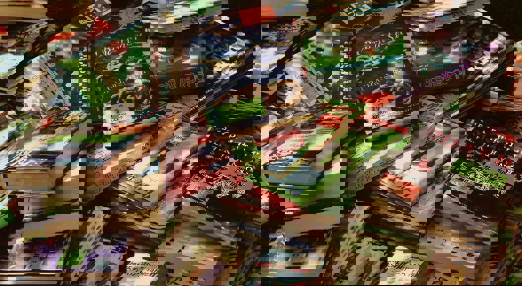 Pile of assorted books with colorful covers on a clearance sale table, featuring various genres and titles