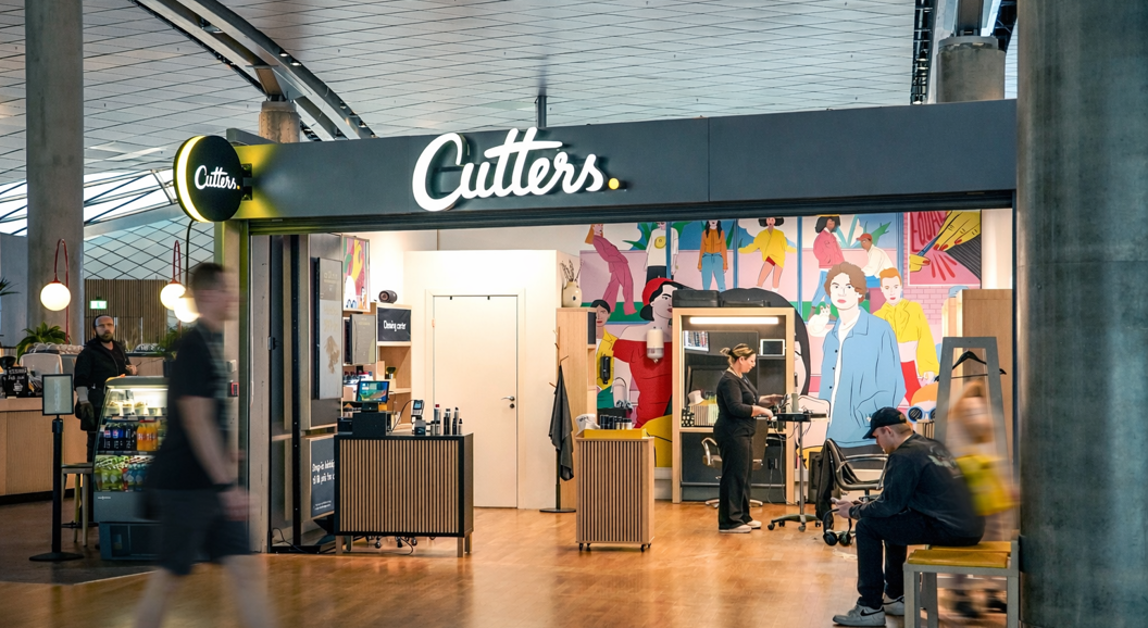 Smiling hairstylist with scissors at a salon, preparing to work on a client's hair