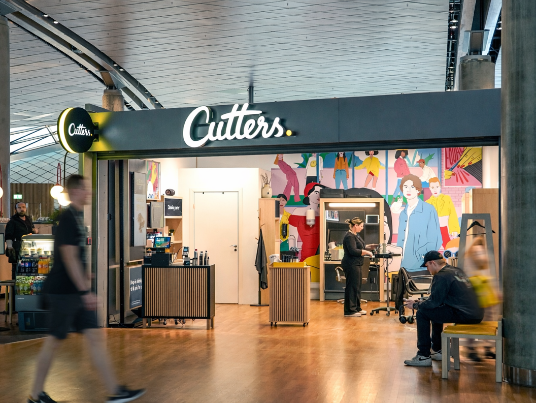 Smiling hairstylist with scissors at a salon, preparing to work on a client's hair