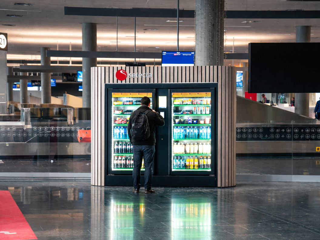 Automat fylt med diverse snacks og sjokoladebarer, inkludert kjente merker, med belyst valgpanel