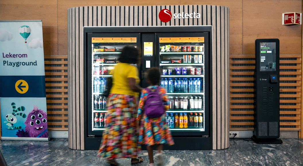 Automat fylt med ulike snacks og sjokoladebarer, inkludert populære merker, med opplyst utvalgspanel