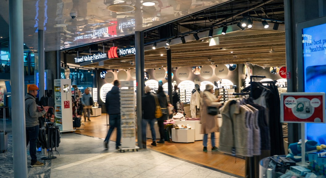 Kvinne ser på solbriller i ein butikk, omgitt av eit stort utval av briller på utstilling