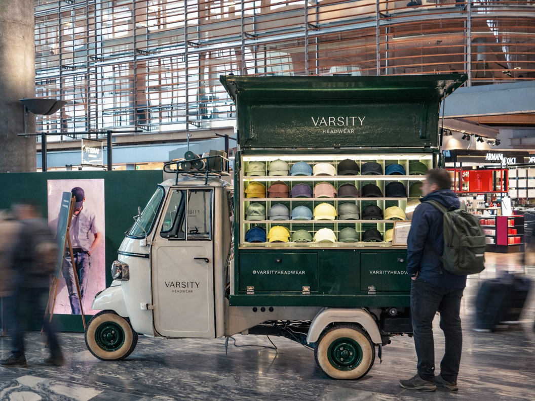 Two stylish caps, one green and one gray, are placed on stacked white concrete blocks with a dark background